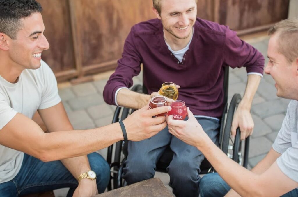 Three young men toasting, one of whom happens to be in a wheelchair.