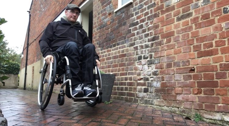Stuart Wheeler, rolling down a side street in his wheelchair.