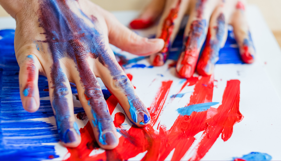 A closeup of someones hands covered in paint taking part in art therapy.
