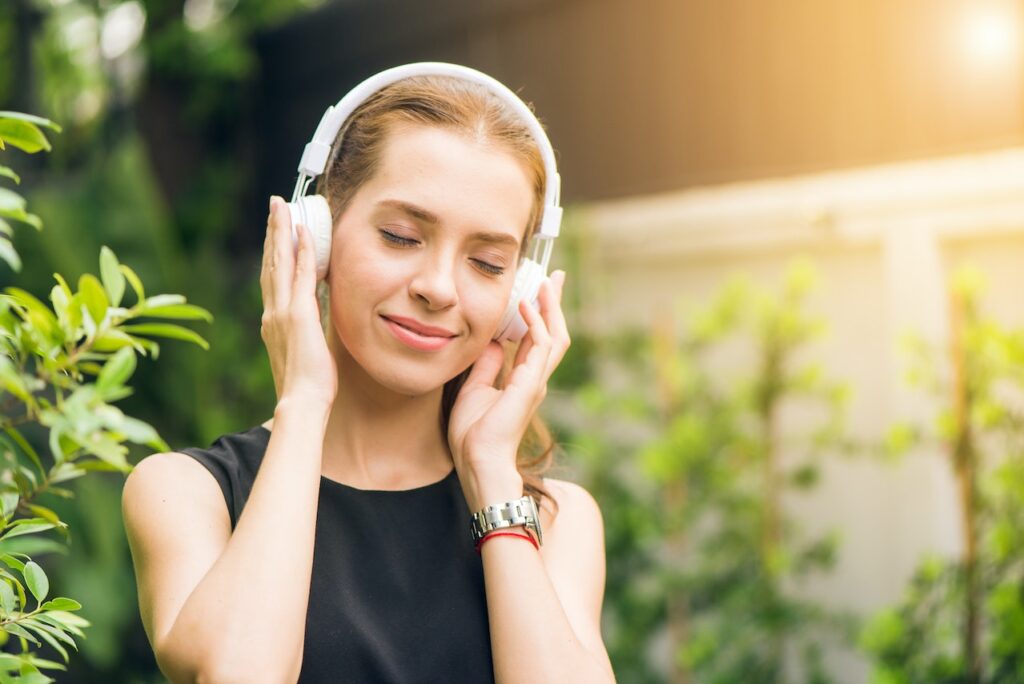 A woman listening to music through headphones with her eyes closed