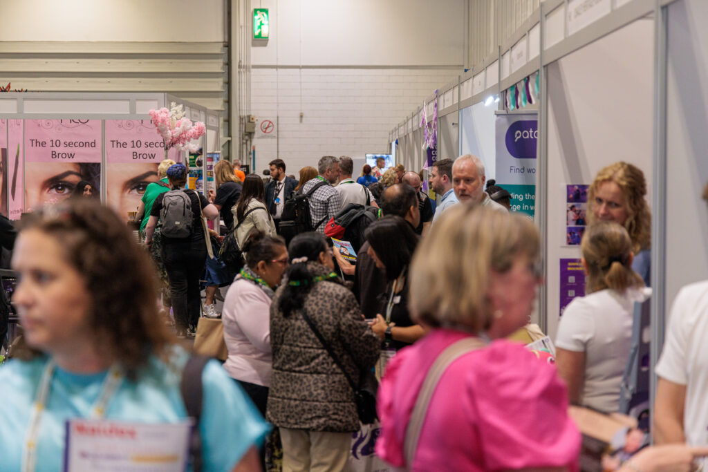 A photo looking down a busy aisle of exhibition stands at Disability Expo.